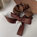 Dettaglio di un elastico in raso marrone caffè con fiocco grande e ciondoli di perle - Marrone