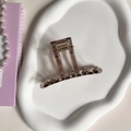 Detail of amber translucent claw clip with metal spring on a white ceramic tray - 11# 8CM One-Line Claw Clip