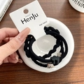 Close-up of black elastic hair ties set with heart charm and floral ornaments on card - Black Pineapple
