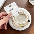 Close-up of beige elastic hair ties with floral charms held in hand on display card. - Beige-Pineapple