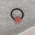 Détail d'un pendentif étoile en résine rose sur élastique noir avec inscription dorée - Rose Pamplemousse