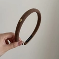 Detalle de diadema de punto marrón con placa metálica Love dorada y etiqueta hecha a mano - café