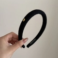 Close-up of black plush headband with golden Love emblem and handmade label detail - Black