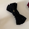 Detail of elegant black velvet bow hair clip with engraved gold oval metal tag - Black