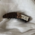 Dettaglio del fermaglio a banana in peluche marrone con orsetto e etichetta in tessuto - Fermaglio Banana Peluche Ricciuto Cachi Con Orso