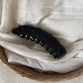 Fermaglio a banana in pelliccia sintetica nera su sfondo di cesto intrecciato - Fermaglio Banana Peluche Ricciuto Nero
