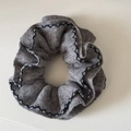 Detailopname grijze gebreide haarscrunchie met blauwe golfsteek en zachte gebreide textuur - Grijs
