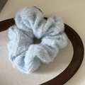 Detailed close-up of a soft light blue plush knit scrunchie on a wooden tray - Blue