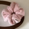 Detailed close-up of a pink plush knit scrunchie with soft faux fur texture on a wood tray - Pink