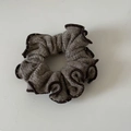 Detailopname van een bruine gebreide scrunchie met ruches en contrasterende biezen in retrostijl - koffiekleur