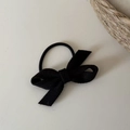 Detail view of a black velvet bow hair tie with a durable elastic band on soft background - Black
