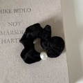 Primer plano de un coletero de terciopelo elegante con perla sobre fondo texturizado - Negro