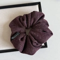 Detail view of burgundy knitted scrunchie fabric texture and branded black woven tag - Purple