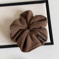 Close-up of dark brown knit scrunchie with vertical texture on a cream display board - Coffee