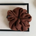 Detail of coffee brown knitted scrunchie with soft ribbed texture and bow label - Caramel color