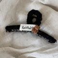 Detail der flauschigen schwarzen Haarklammer mit braunem Bären und gewebtem Etikett - Plüschbär-Stil / Schwarz