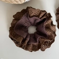 Detalle de coletero vintage marrón de punto con bordes de encaje sobre un fondo blanco - Coletero Encaje Café