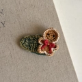 Macro shot of handcrafted crochet gingerbread man hair clip with gold trim on linen - Gingerbread Man Green Striped Clip (18#)