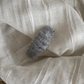 Gros plan d'une pince à cheveux en laine tricotée grise avec texture à vagues rétro - Gris
