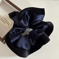 Detailopname van een elegante donkerblauwe satijnen scrunchie met een zwarte fluwelen rand - Marineblauw Zwarte Rand