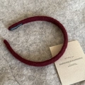 Detail of burgundy knit headband with handmade woven label on soft plush background - Burgundy
