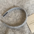 Detail of grey knitted headband featuring soft texture and black handmade fabric label - Gray