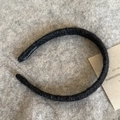 Detailed view of handmade black knitted headband with a woven label on knit background - Black