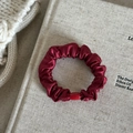 Close-up of a burgundy satin scrunchie with a matching bead on a cozy fabric background - 2# Red Small Scrunchie