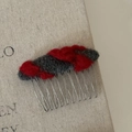 Detailansicht eines Vintage-Filzkamms mit rot-grauem Garn auf einer Metallbasis - Grau Rot Gestreifter Haarkamm
