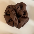 Macro detail of chocolate satin scrunchie with soft silk texture and voluminous pleats - Brown Satin
