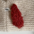 Close-up of deep red lamb wool hair clip on a white knit background showing soft texture - Red