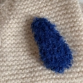 Detailed view of a plush navy blue lamb wool hair clip on soft knit texture - Dark Blue