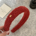 Dettaglio del cerchietto in pile rosso con un elegante elemento in metallo dorato - Borgogna
