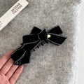 Détail de la pince à cheveux en velours noir avec surpiqûres à pois et décor en métal doré - Pince Banane Nœud Noir