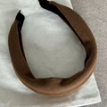 Detail van een dikke bruine fluwelen haarband met vulling op een wit stoffen zakje - Karamel