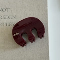Gros plan d'une pince à cheveux rouge bordeaux en résine avec finition brillante - Rouge Vin Trois Griffes (Lettrage Doré)