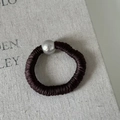 Detail of dark brown satin hair tie with a polished silver metallic bead on linen fabric - Brown
