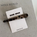 Detail shot of leopard print acrylic hair clip on packaging over a textured book - Long Duckbill Clip / Grey Leopard
