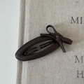 Detail shot of the dark brown leather bow hair clip with a classic metal BB clip base - Oval Shape (Bow) / Brown