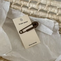 Primer plano de la horquilla de clip marrón mate en tarjeta con una estética minimalista - Marrón