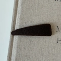 Primer plano de una horquilla triangular de tela marrón oscuro sobre lino beige - Marrón