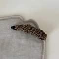 Detail view of vintage dark brown floral banana hair clip on soft quilted linen fabric - Khaki White Texture Floral