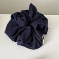 Detailaufnahme von dunkelblauem Denim-Haargummi mit minimalistischem weißem Webetikett - Denim Haargummi / Dunkelblau