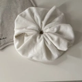 Close-up of soft white velvet scrunchie with brand label on minimalist linen background - White