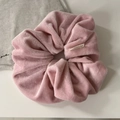 Detailed close-up of soft pink velvet scrunchie featuring premium pleated texture and woven label - Pink
