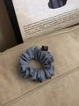 Detail eines blauen Satin-Haargummis mit Punkten auf einem beigen strukturierten Sofa - Blau mit weißen Punkten
