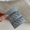 Set di fermagli per capelli in maglia grigia su carta tenuta da una mano donna - Righe Grigie