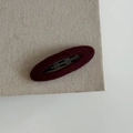 Detailed view of a plush dark red velvet oval BB hair clip on a textured fabric background - Oval Hair Clip / Burgundy