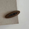 Detailed view of a dark brown wool felt BB hair clip on a beige textured fabric background - Oval Hair Clip / Coffee