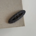 Close-up of a dark grey plush wool hair clip with a hollow oval design on a linen surface - Oval Hair Clip / Gray